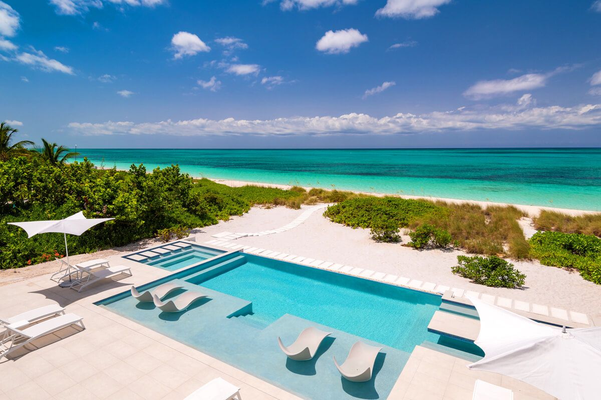 The pool sits just above the white sands of Grace Bay Beach