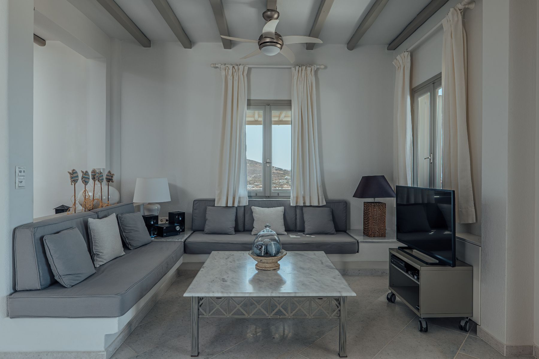 Open-plan living with cozy lounge, featuring spacious sofa area, flat-screen television, and access to the terrace. 