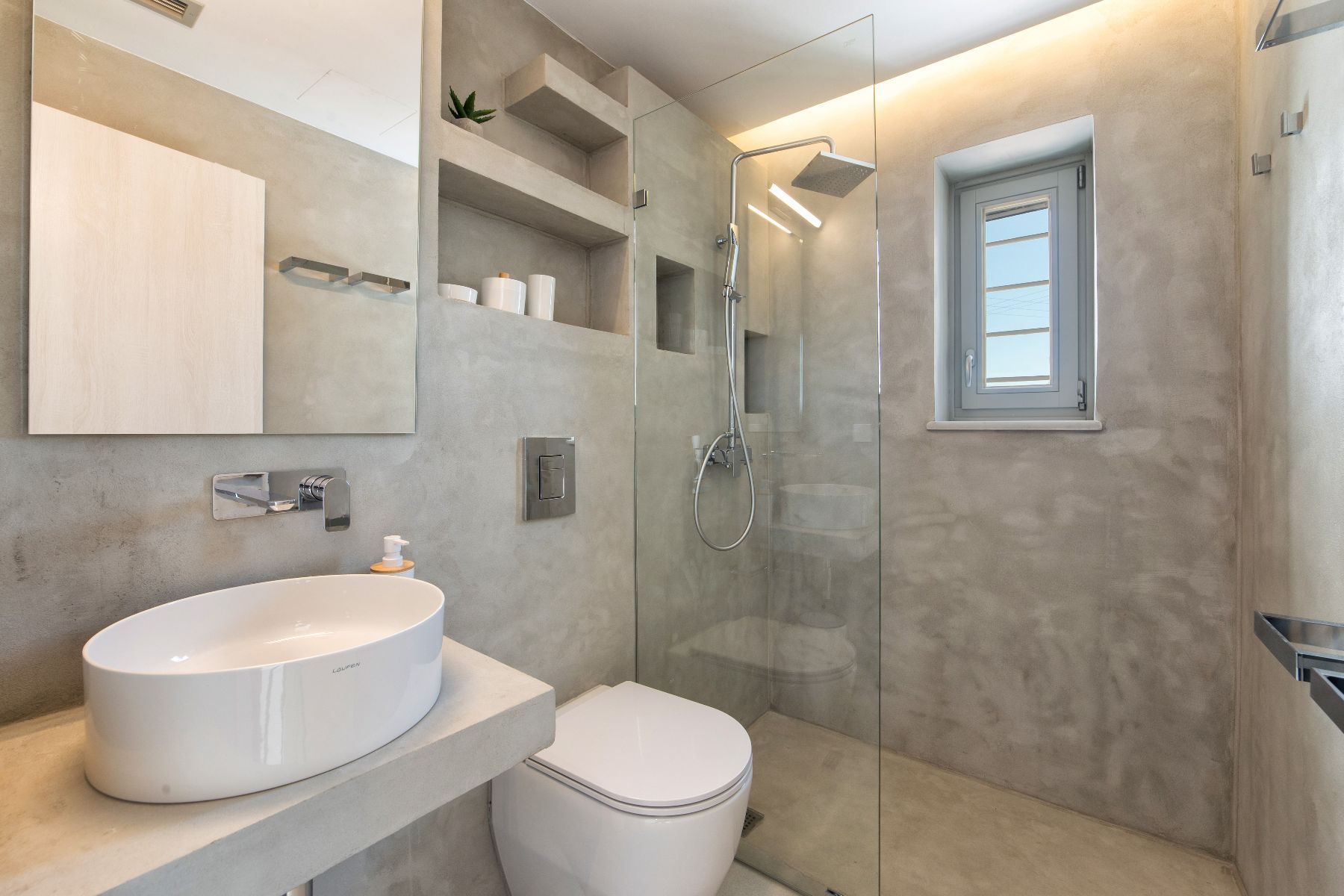 Modern ensuite bathroom with large walk-in shower, round basin and concrete vanity unit. 