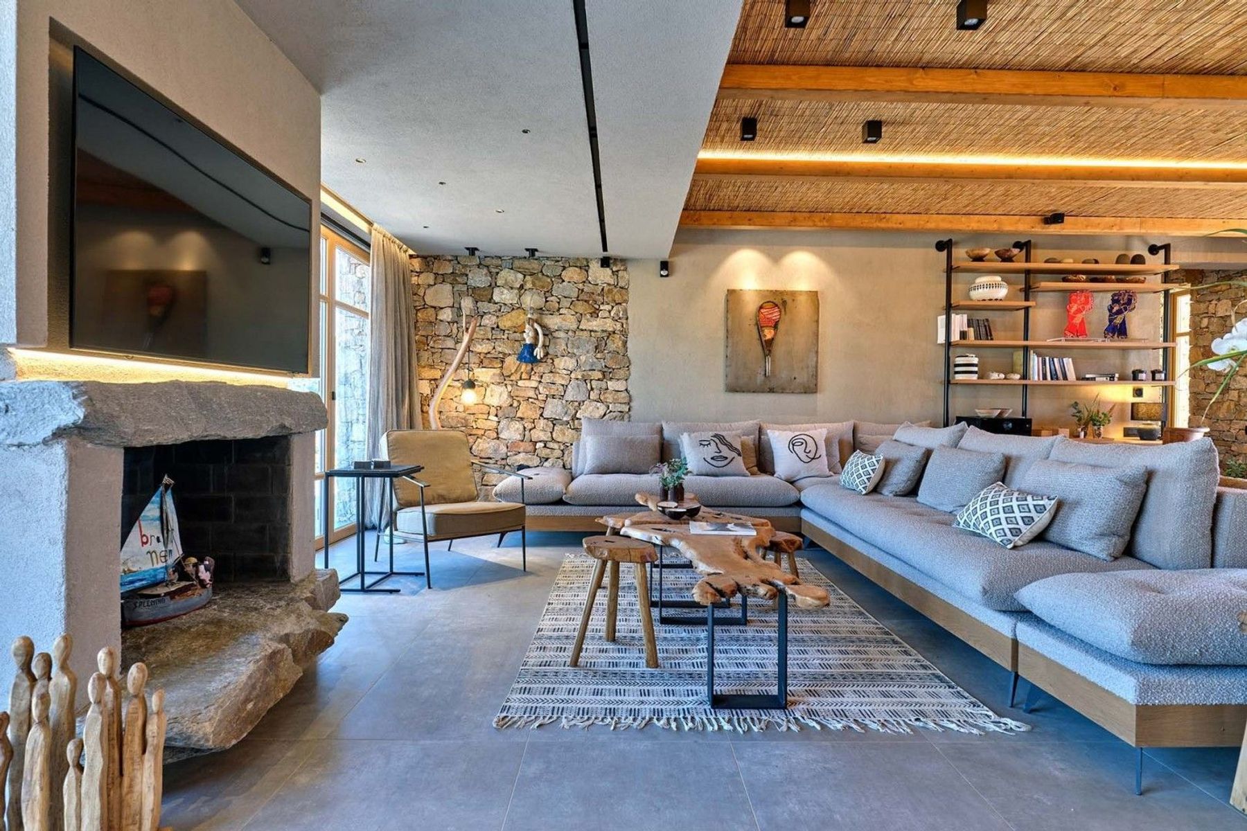 Modern living area with comfy sofa, television, fireplace, and access to the pool terrace.