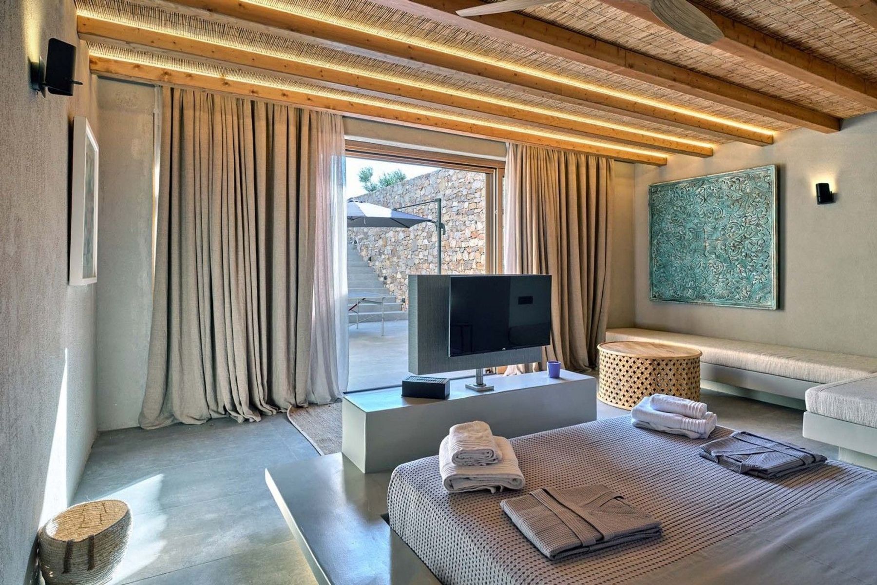 Double ensuite bedroom with television and separate seating area. There is also direct outdoor access.