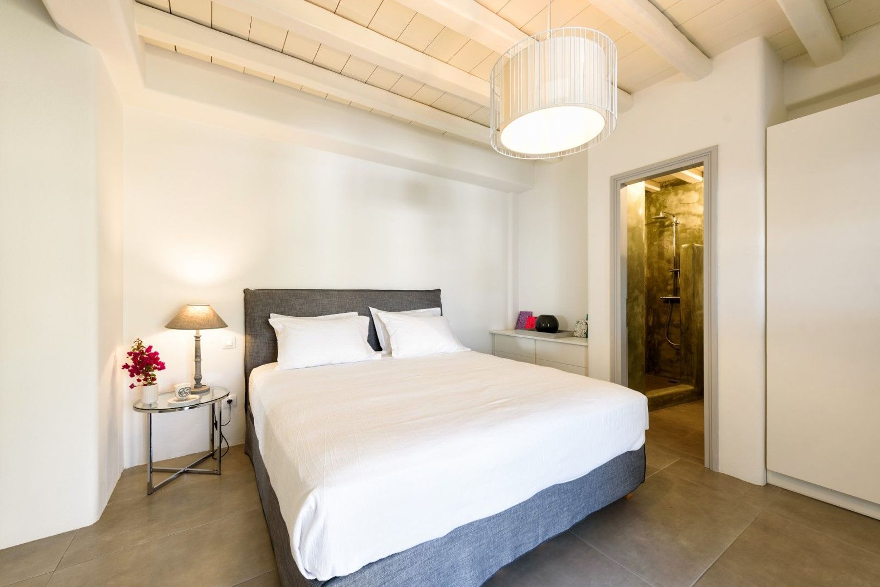 Double ensuite bedroom decorated with cement surfaces, grey tones, and wooden ceilings.