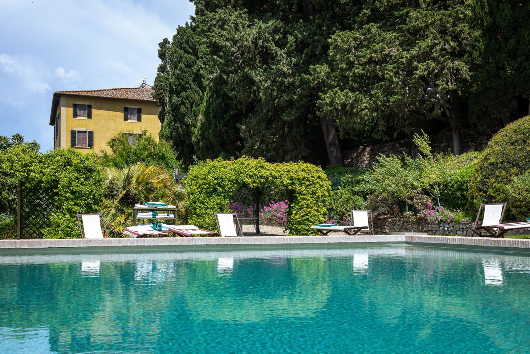 The stunning infinity pool surrounded by lush  gardens, offering a private oasis for relaxation and sunbathing.