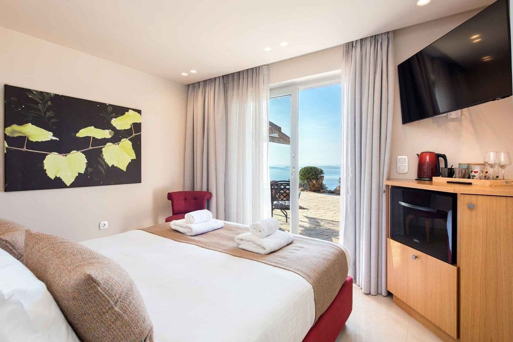 Double ensuite bedroom with a king-size bed, television and access to the lower-level terrace with a garden view.
