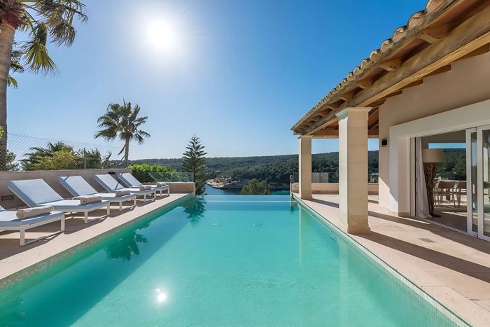 Large heated infinity pool, flanked by sun loungers and overlooking the sea.